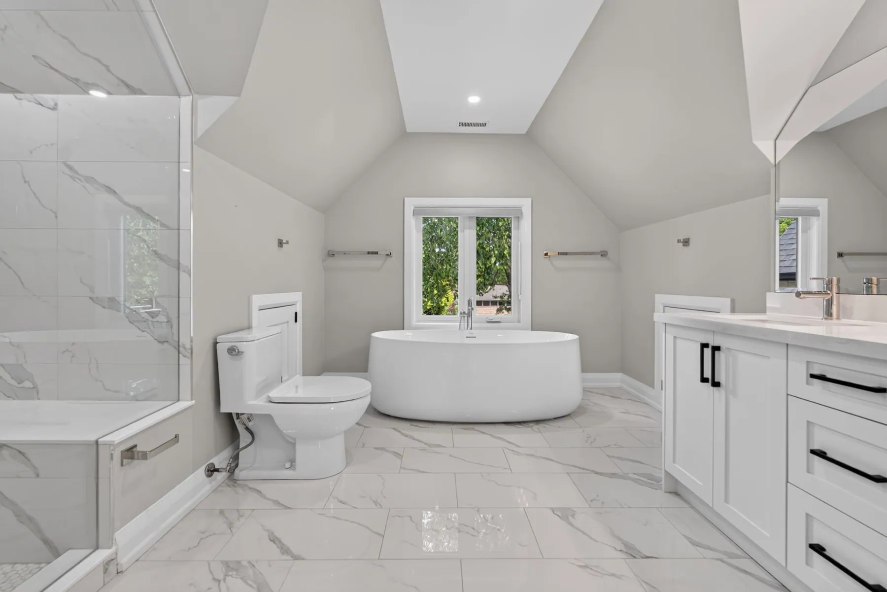 Vaulted ensuite with freestanding tub and marble tile